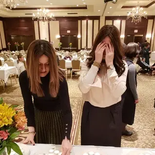 Women preparing Shabbat candles, one covering eyes