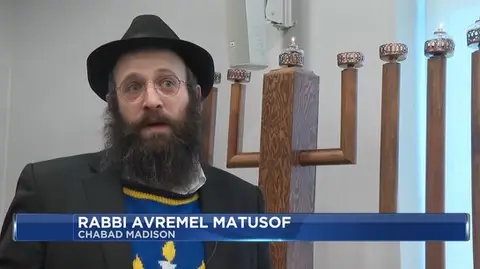 Rabbi being interviewed in front of menorah