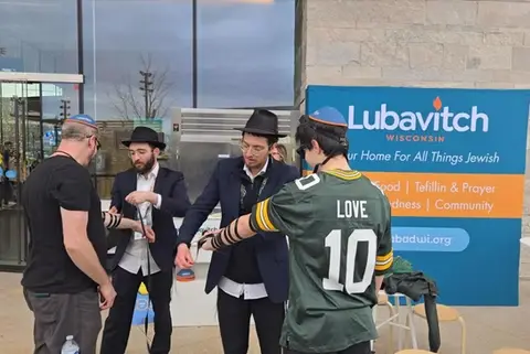 Student rabbis are wrapping Tefillin on the arms of Jewish fans attending the NFL draft