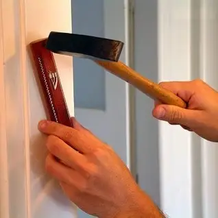 Hands installing a mezuzah on a doorframe