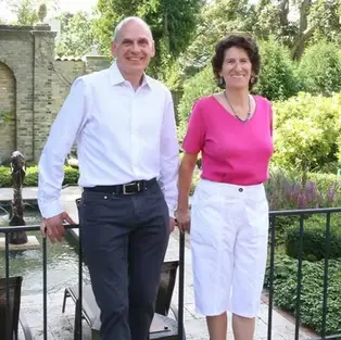 Smiling man and woman standing in a garden with a fountain
