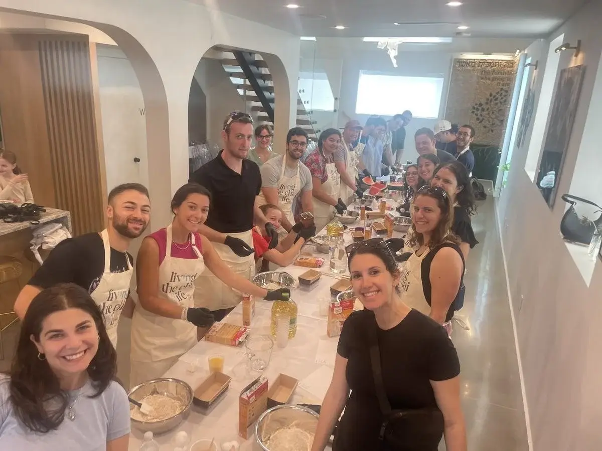 Volunteers gathered around a long table baking together at a Johnny's Giving Kitchen session