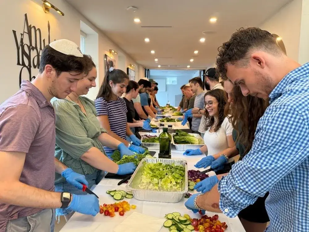 Volunteers chopping fresh vegetables side by side at a long prep table
