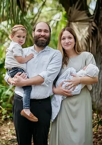 A family of four posing outdoors in a lush garden