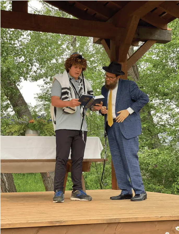 Adam, on the day of his Bar Mitzvah, putting on tefillin with Rabbi Chaim. ‍