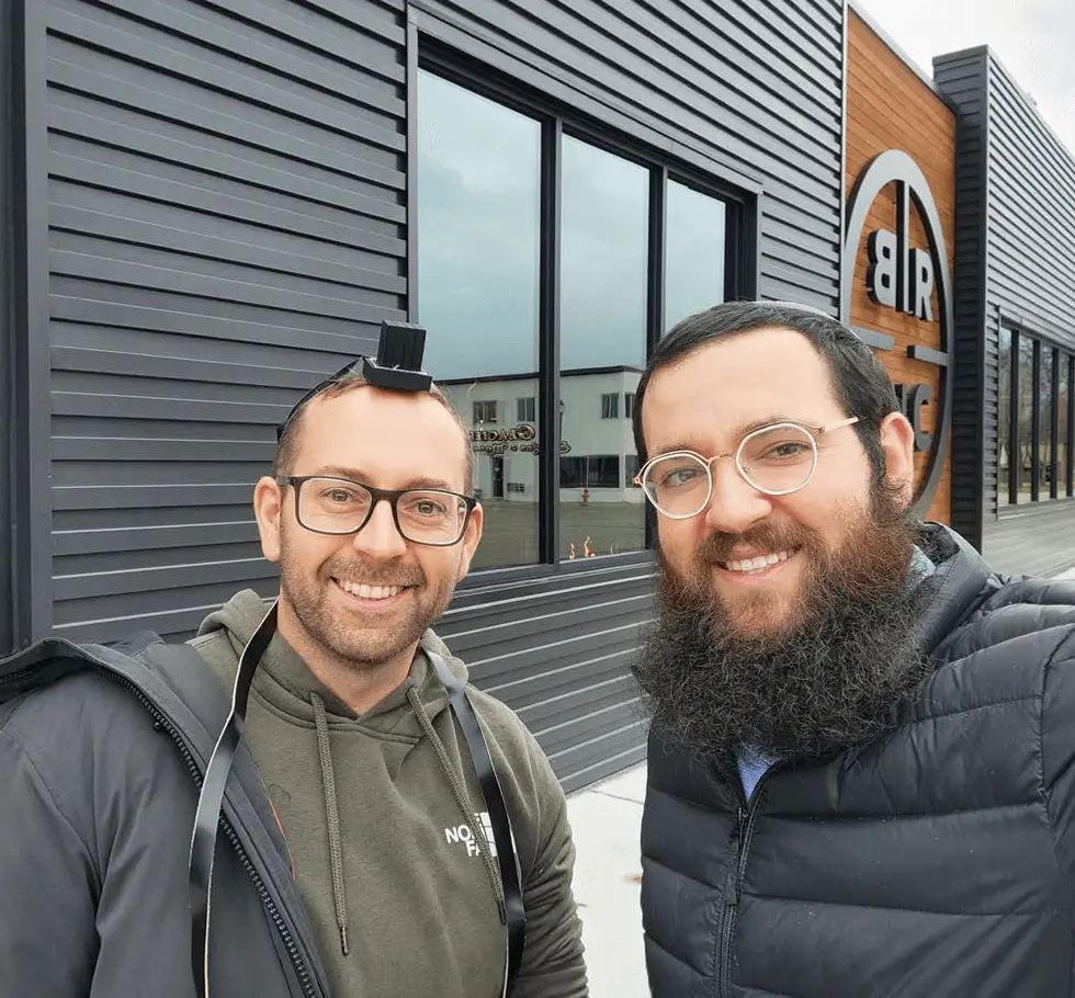 Simon putting on tefillin with Rabbi Shneur Wolf at Black Rifle Coffee Company the day after he moved to Kalispell.