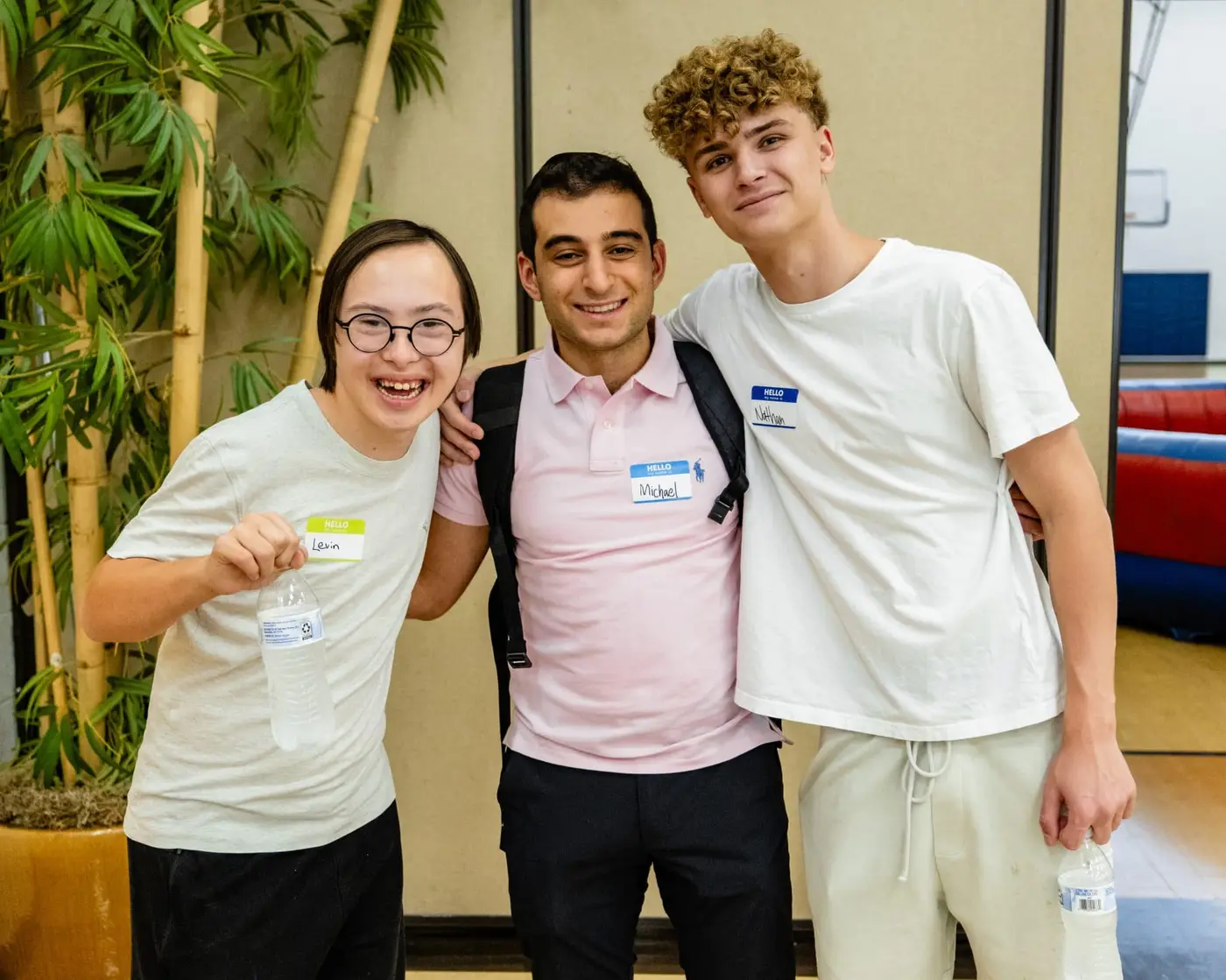 Three smiling young men stand together, with "Michael" and "Hello, My Name Is: Vinnie" on name tags.