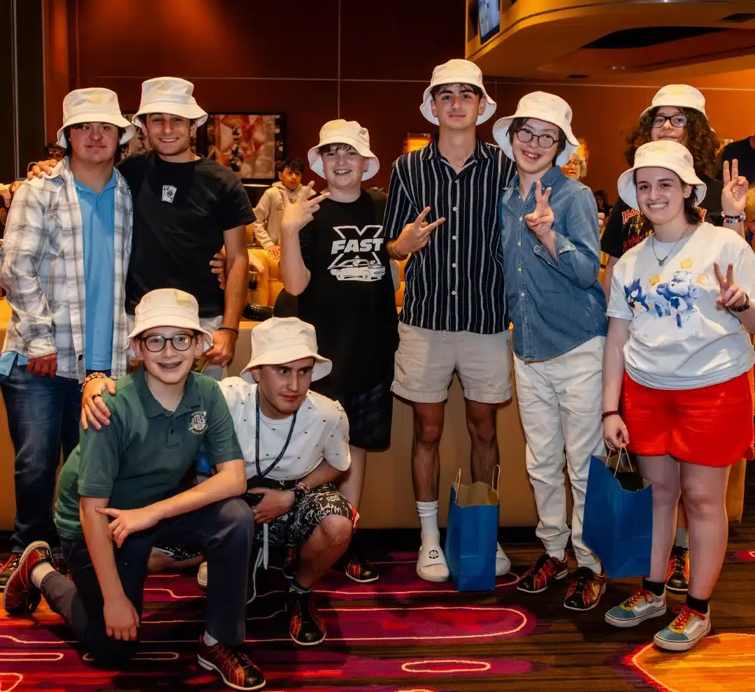 A group of ten young people, mostly wearing white bucket hats, pose and smile for the camera.