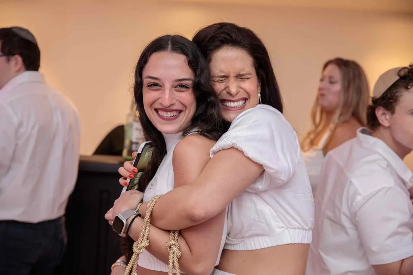 Two friends laughing mid-embrace at a CYP DoBo White Party.
