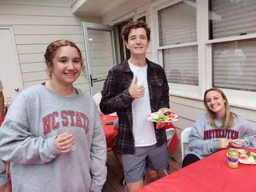 Three young people enjoying food and drinks outdoors.