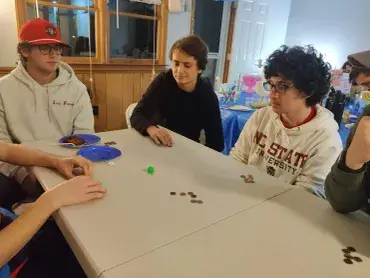 Group playing a tabletop game involving coins.