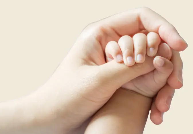 Close-up of two hands gripping each other, one adult and one child's hand.