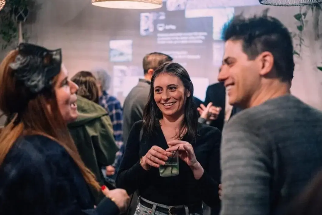 Group of people socializing at a party or event, smiling and holding drinks.