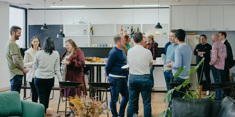 Group of parents socialising during a support meeting in a modern kitchen space.