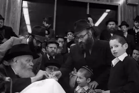 Rabbi Shmuel Azimov receiving a dollar from the Rebbe