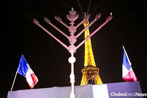 A menorah at the base of the Eiffel Tower, flanked by two French flags